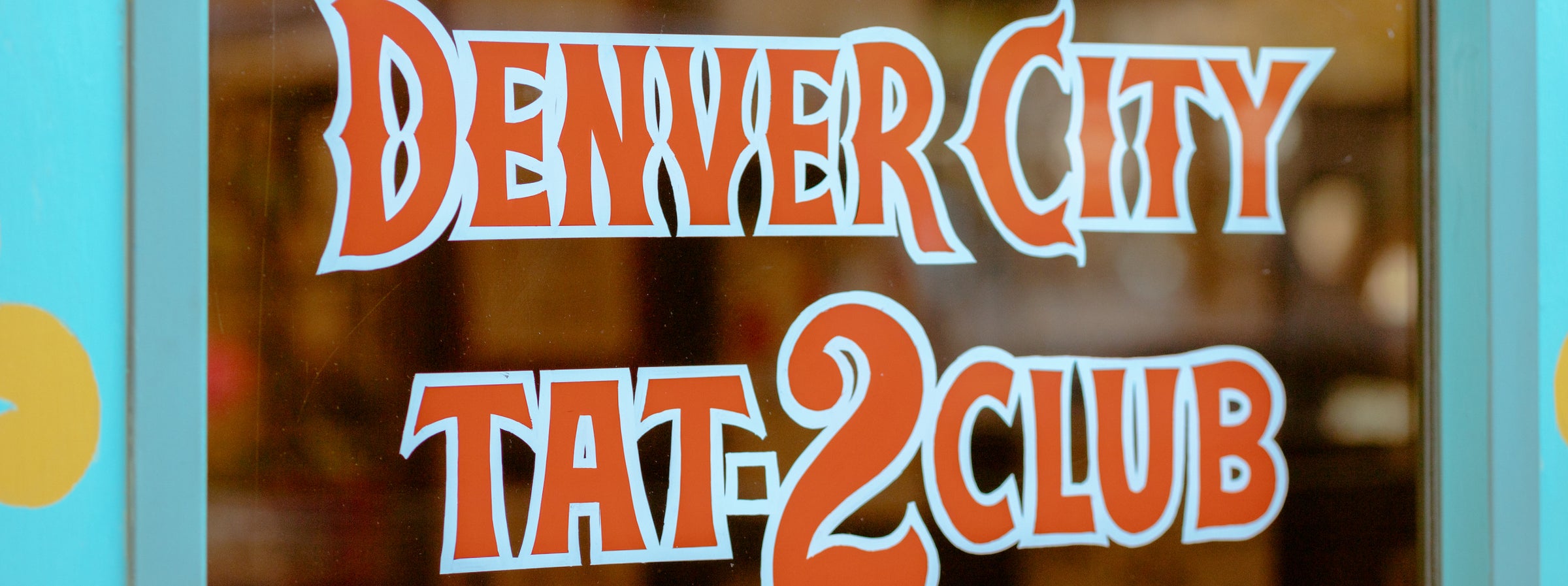 The hand painted Denver City Tat-2 Club sign on the shop's front window